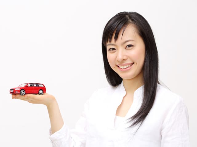 掌に車をのせている女性の画像